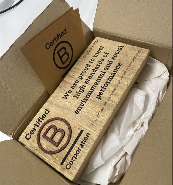 A Certified B Corporation plaque in a cardboard box with packaging paper.