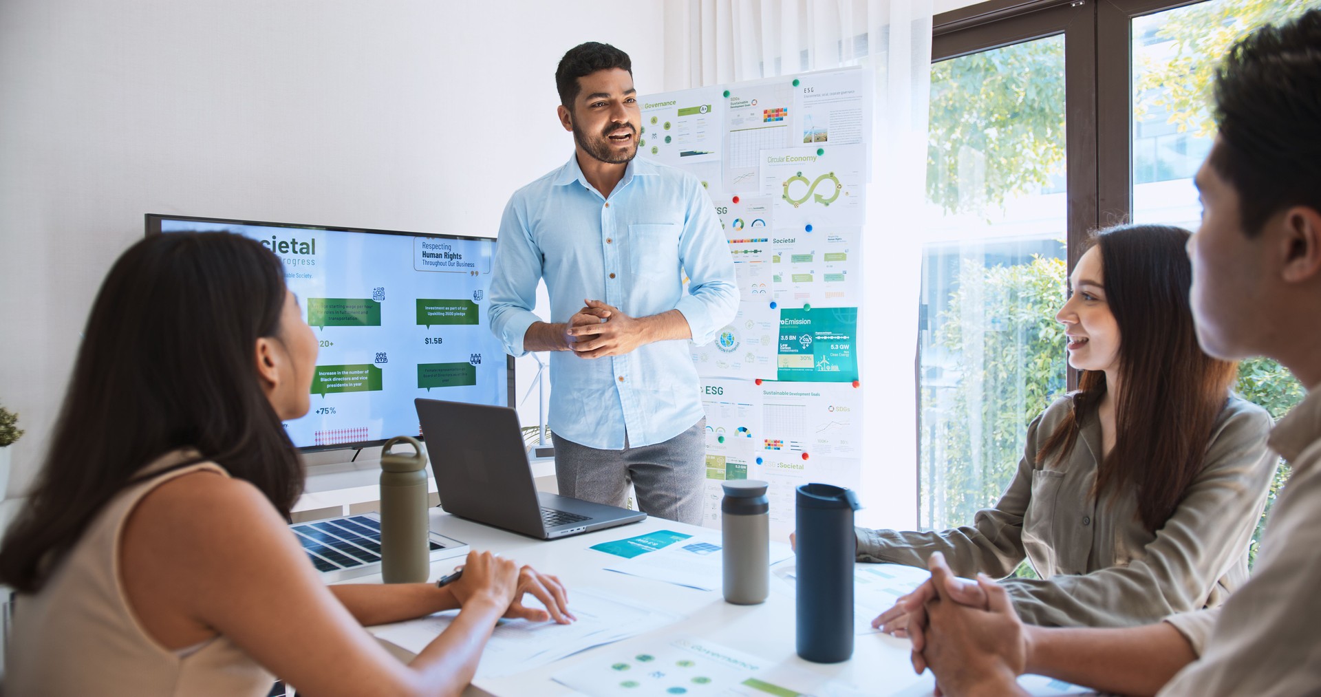 Asian Indian man lead young group of multiethnic businesspeople in team meeting, using laptop computer for ESG topic presentation on monitor. Sustainable business practice, people work at home concept